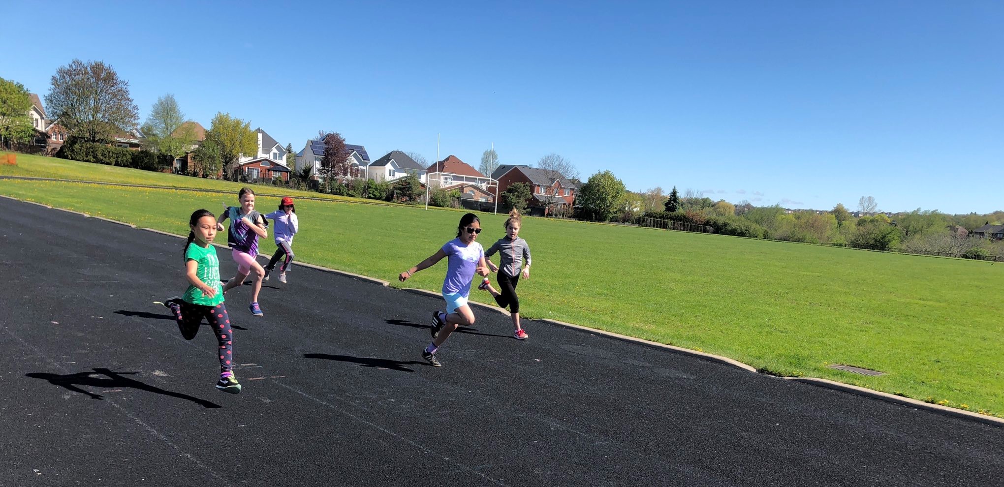 Five female students running on an outdoor track